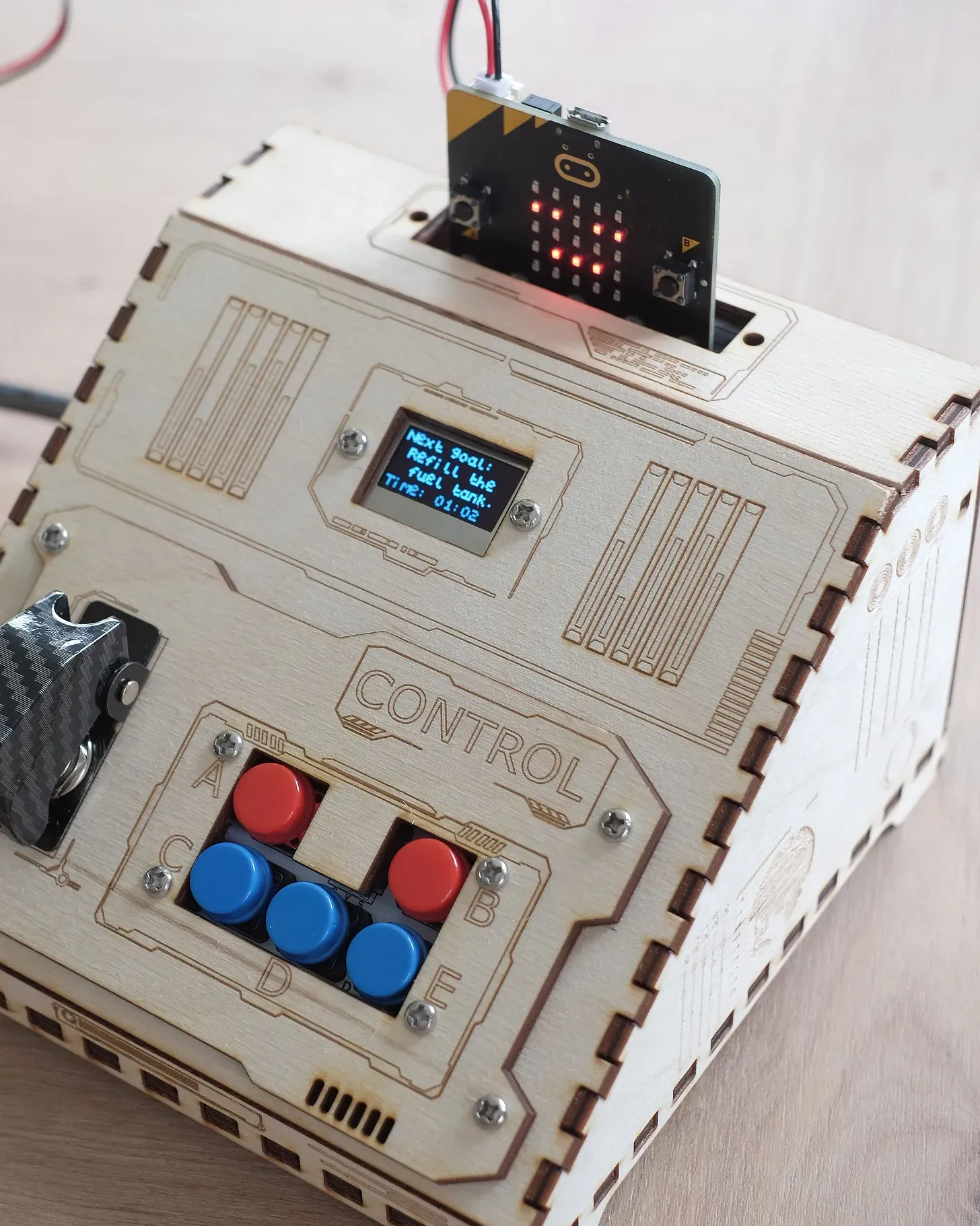 A laser cut wood console, with buttons, switches and a small screen showing instructions.