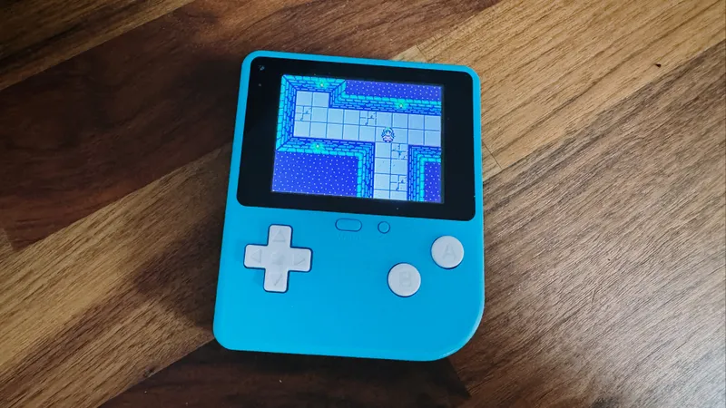 A handheld MakeCode Arcade console on a wooden table, running a maze game.